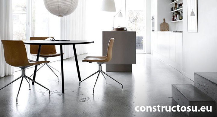 Living cu masă și scaune pe pardoseala de beton